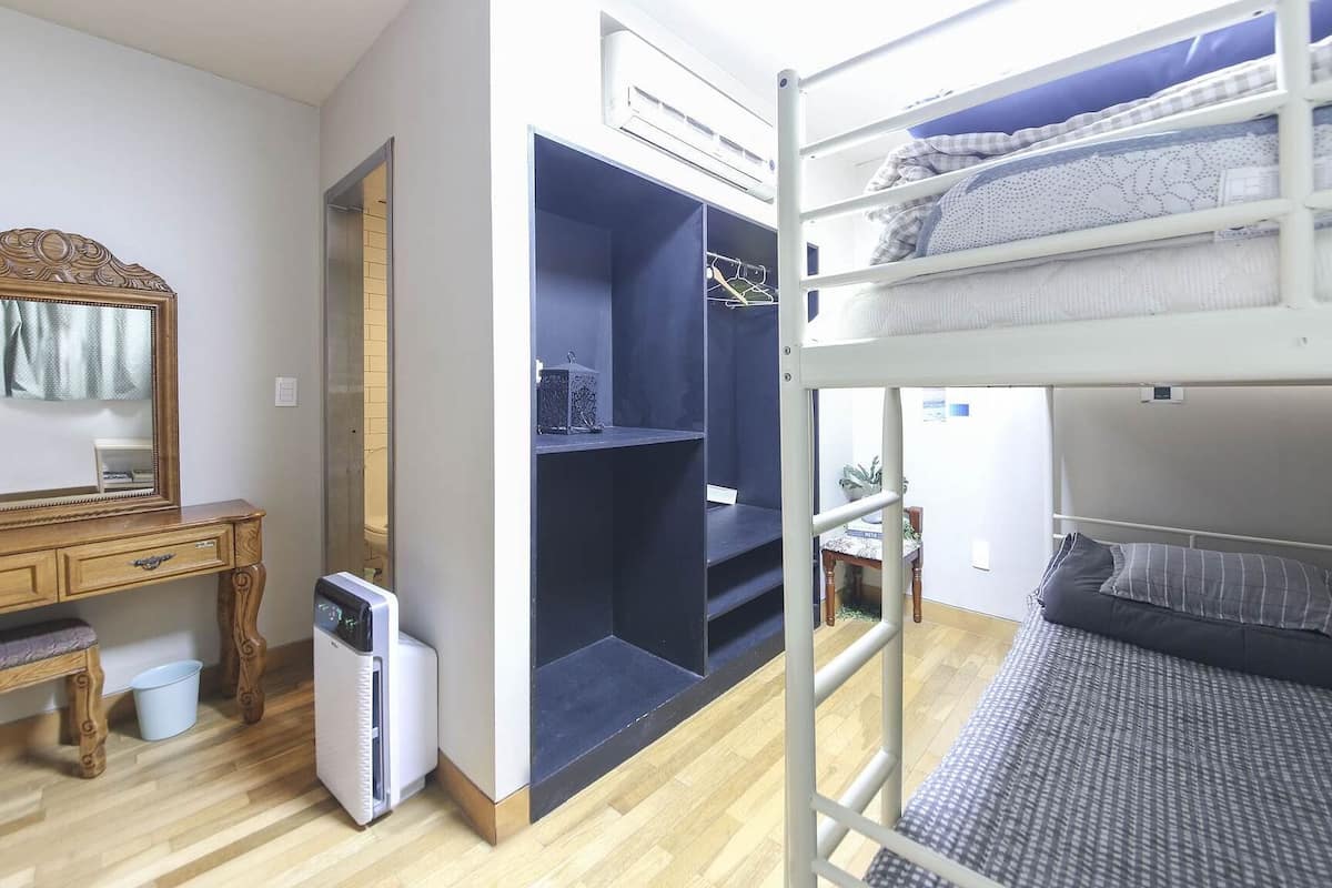Una habitación compacta con una litera, un escritorio de madera con espejo y un armario con repisas.