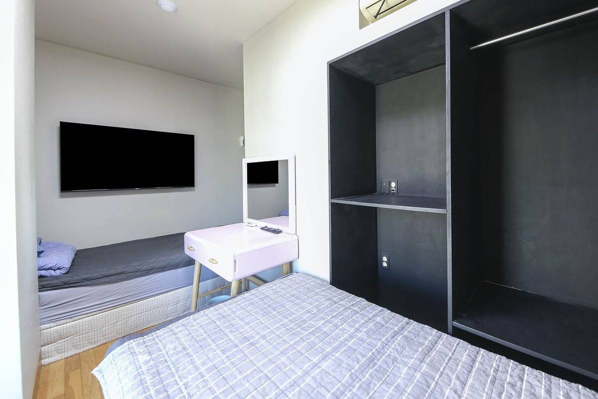 Un dormitorio con cama, escritorio, televisor y armario.