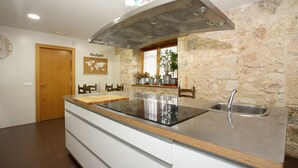 Una cocina moderna con salpicadero de piedra, un lavamanos de acero inoxidable y una isla grande con estufa integrada.