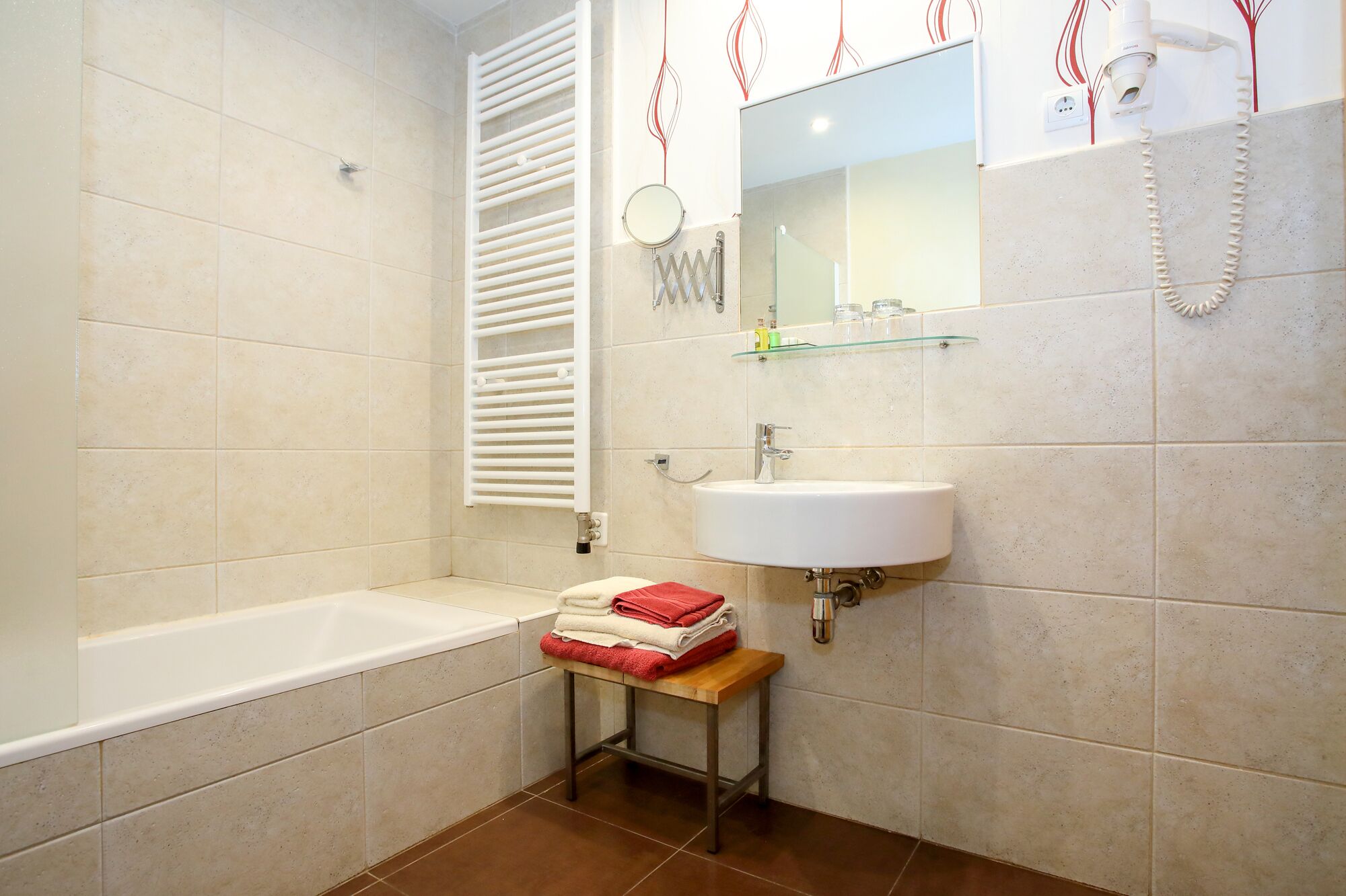 Ein Badezimmer mit einer Badewanne, einem Waschbecken, einem Spiegel und einem Handtuchhalter.