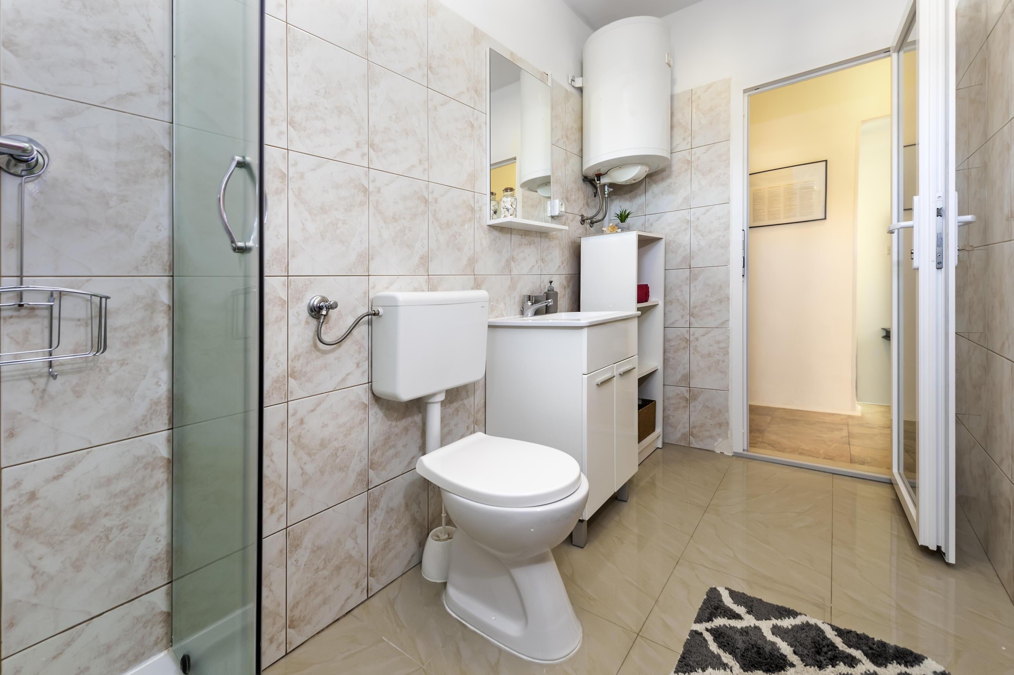 A modern bathroom with a toilet, sink, and shower.