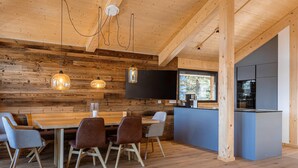 A modern kitchen with a large island, wooden walls, and a flat-screen TV. - Natural chalet with sauna and hot tub (Turrach)