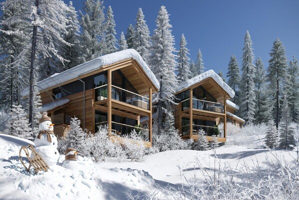 A modern wooden cabin with a balcony, surrounded by snow-covered trees. - Natural chalet with sauna and hot tub (Turrach)