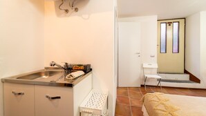 Een kleine keuken met een spoelbak, een klein aanrecht en een stoel bij de deur.