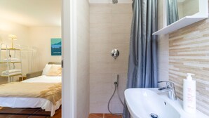 Een badkamer met een douche, wastafel en een bed.