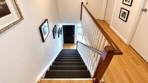 A staircase with a wooden handrail, carpeted steps, and a door at the top.