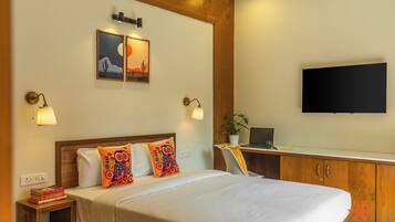Een hotelkamer met een bed, nachtkastjes, een bureau, een televisie en kunst aan de muur.