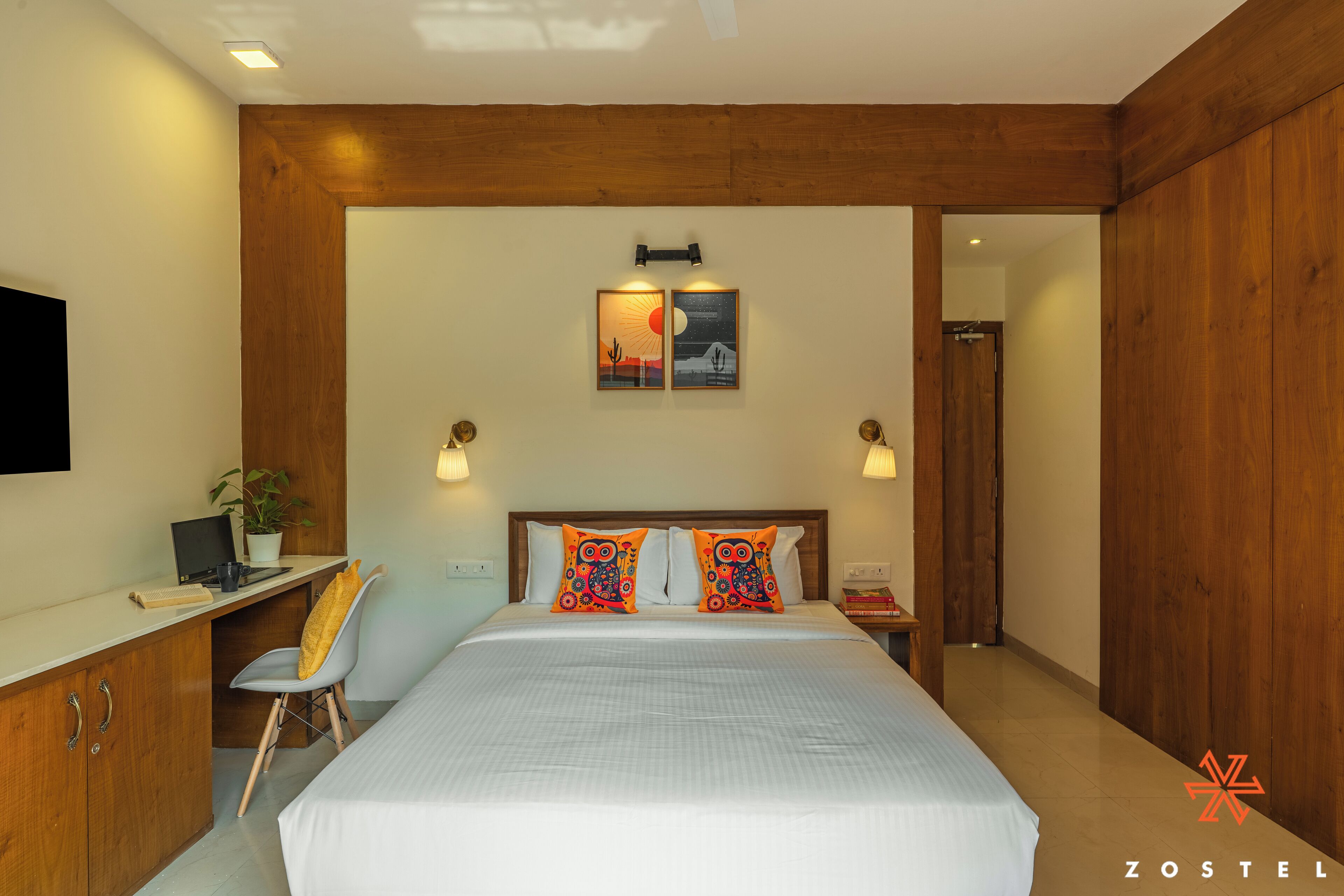 Un dormitorio con cama, escritorio, silla y mesita de noche con lámpara.