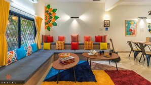 A modern living room with a sofa, coffee table, and a dining area. - Zostel Pune (Pune)