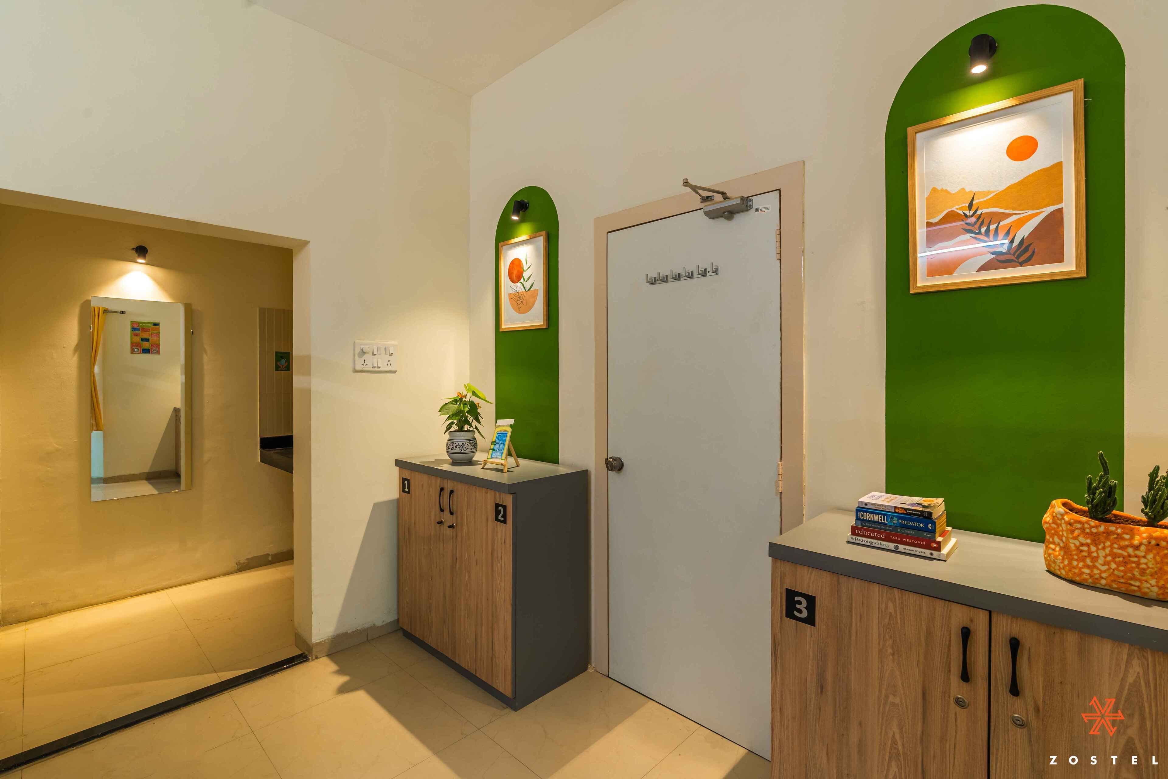 A hotel lobby with a reception desk, a green wall with a framed picture, and a door with a number sign.