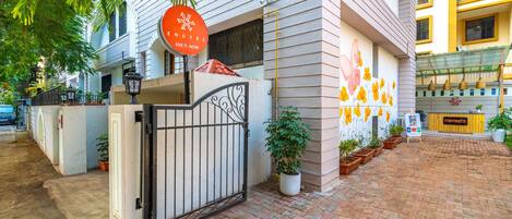 A hostel with a gated entrance, potted plants, and a mural on the wall.