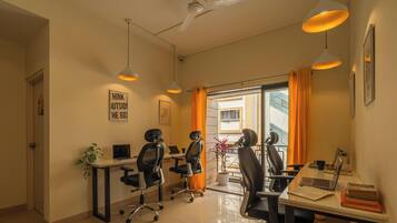 A modern office space with two desks, office chairs, and pendant lighting.