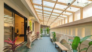 A covered walkway with wooden beams, potted plants, and benches. - Zostel Pune (Pune)