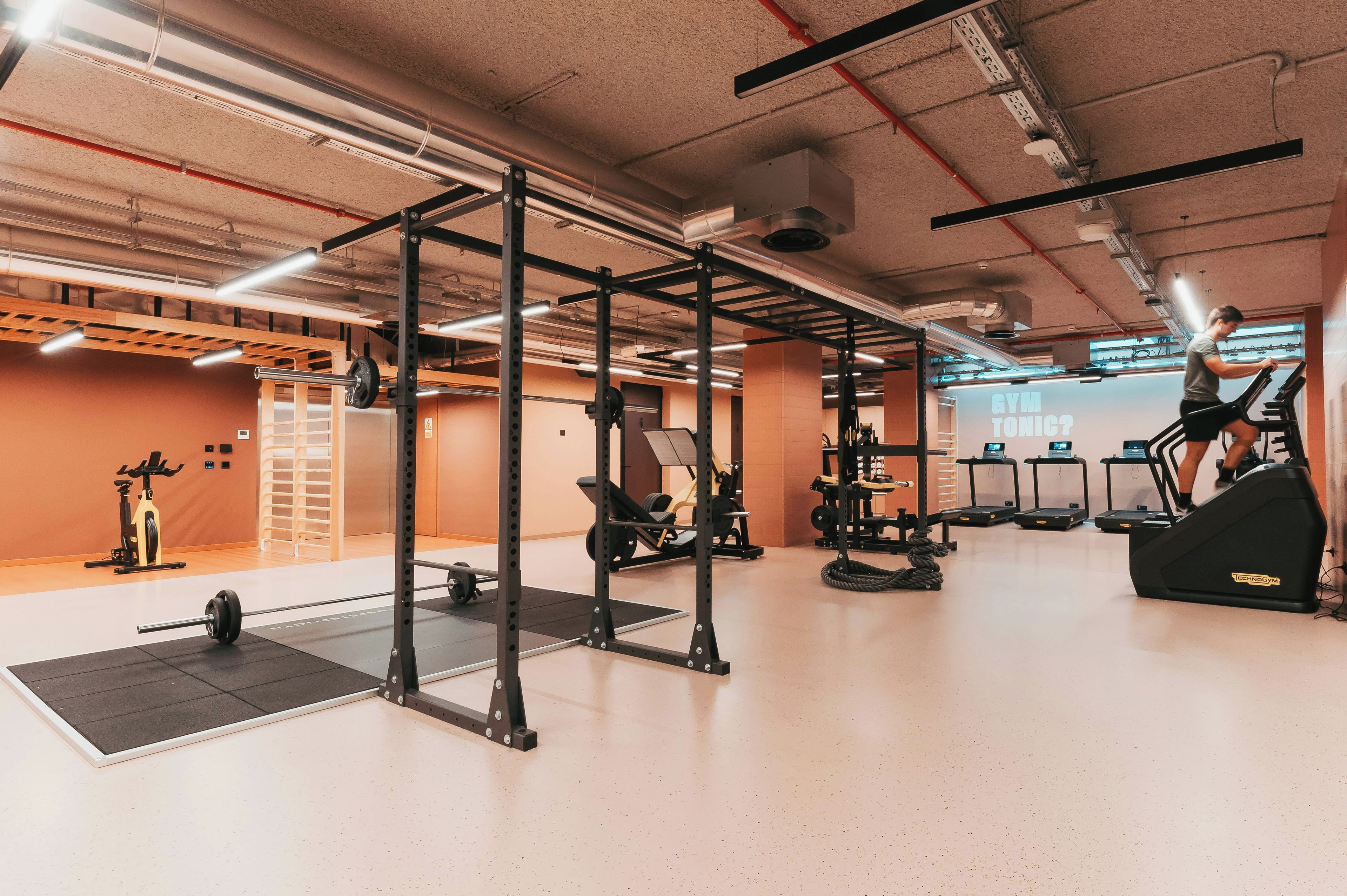 Une salle de sport équipée de matériel d’exercice, de tapis de course et d’un support pour les exercices de squat.