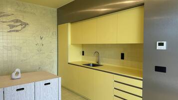 Una cocina moderna con armarios amarillos, un lavamanos de acero inoxidable y un panel de control en la pared.