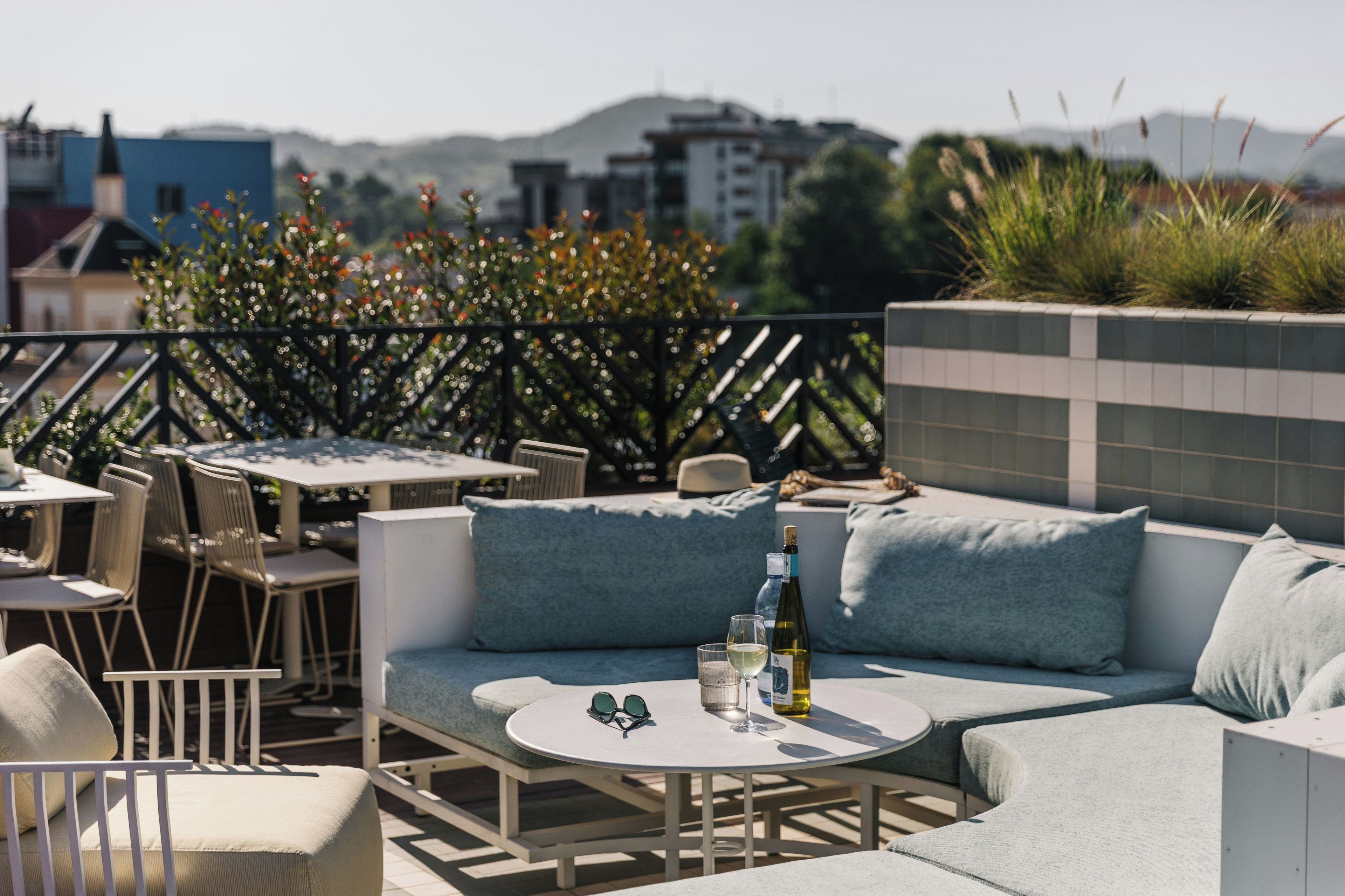 An outdoor seating area with tables and chairs, a sofa, and a bottle of wine.