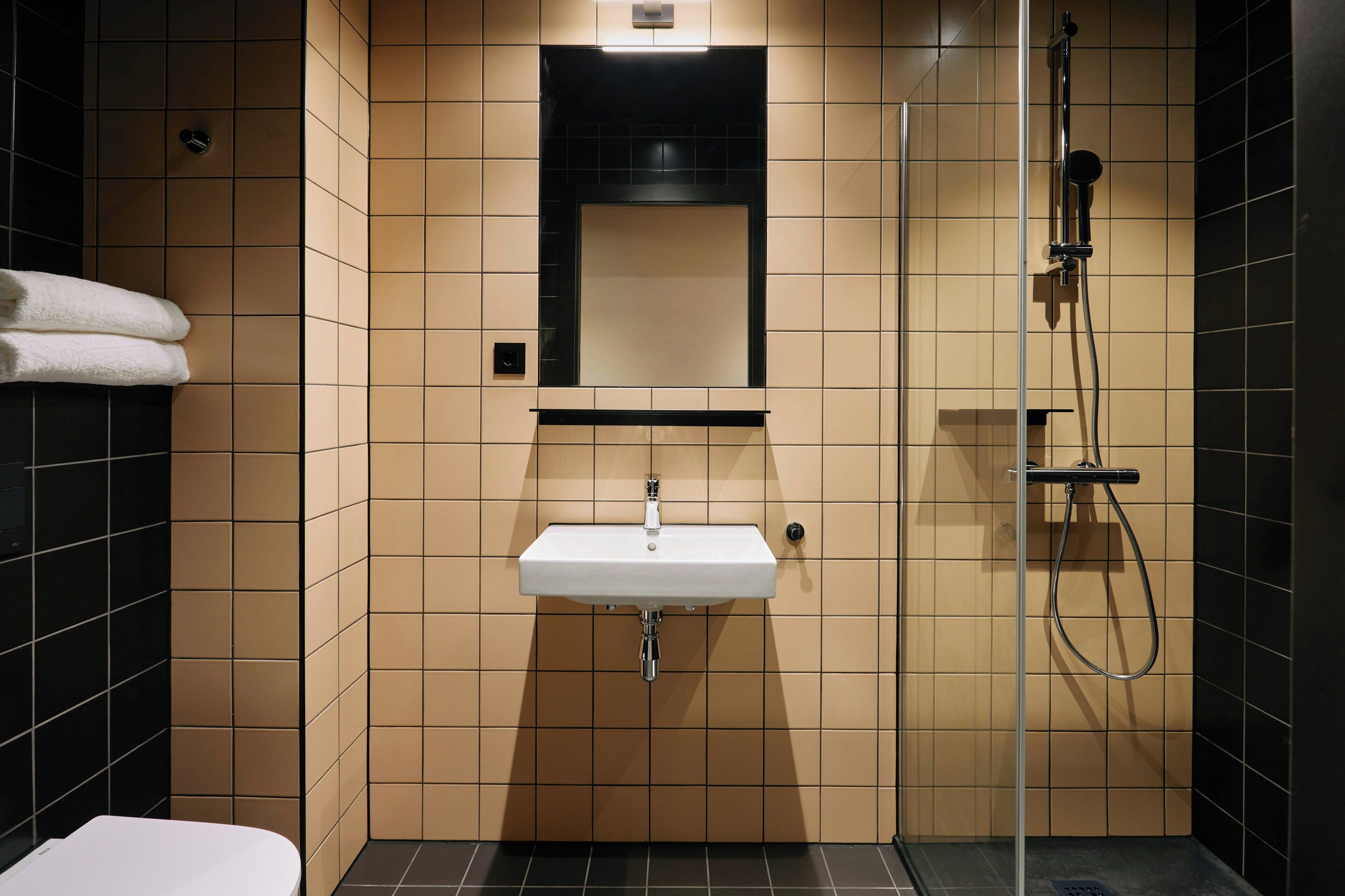 A bathroom with a sink, mirror, and shower.