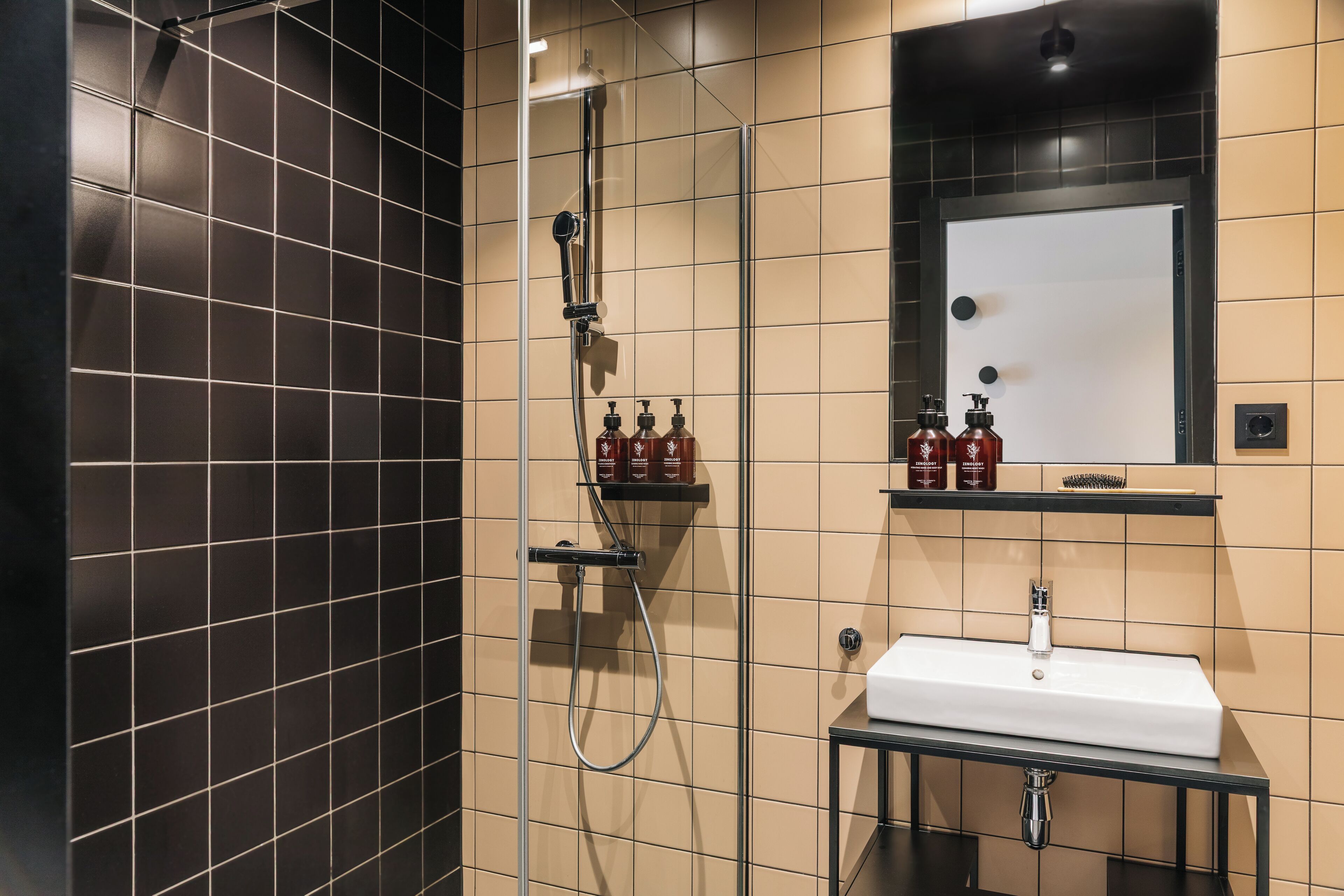A modern bathroom with a glass-enclosed shower, a white sink, and a mirror above it.