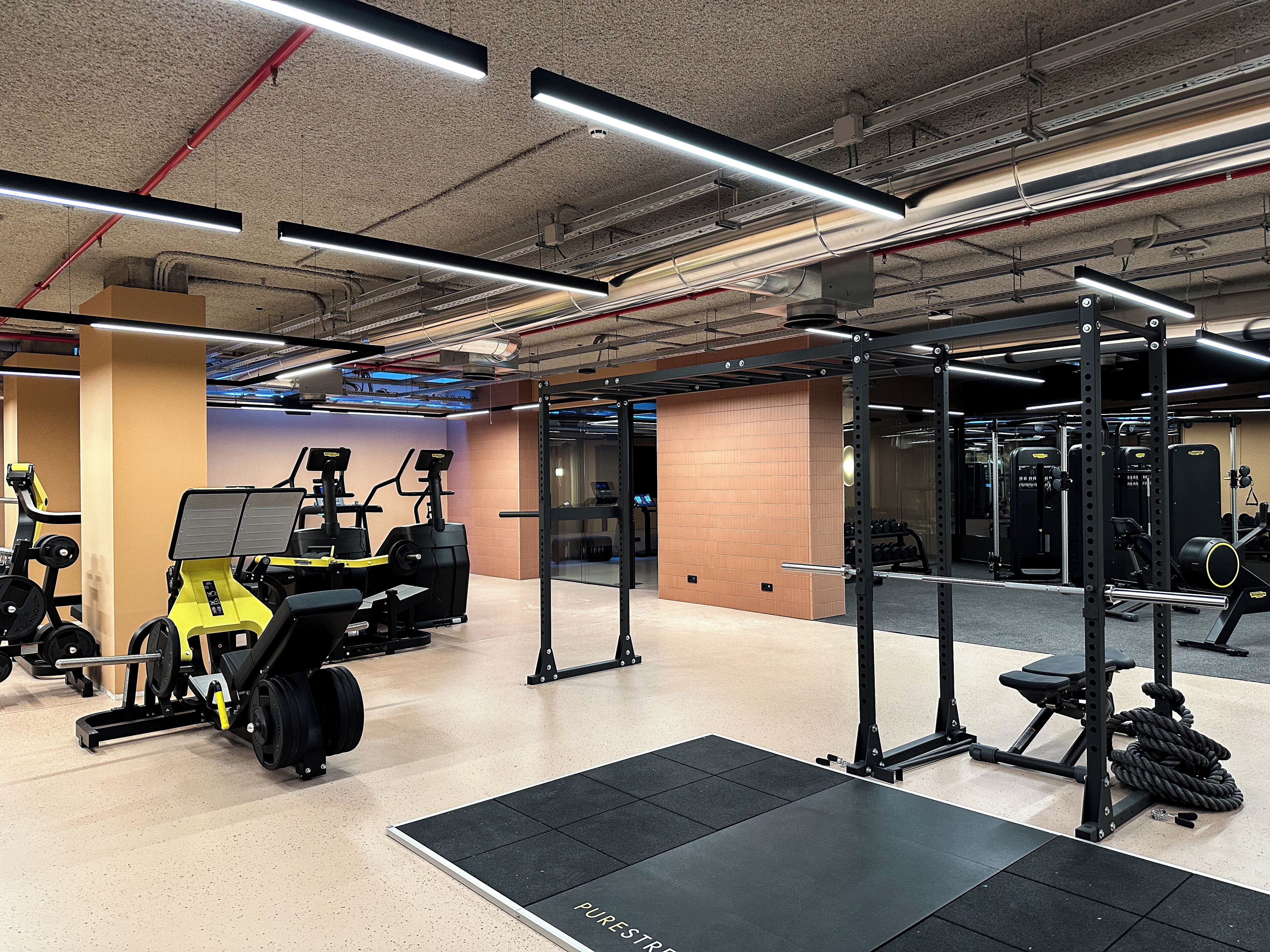 Un gimnasio con equipo de levantamiento de pesas, cintas de correr y un espejo grande.