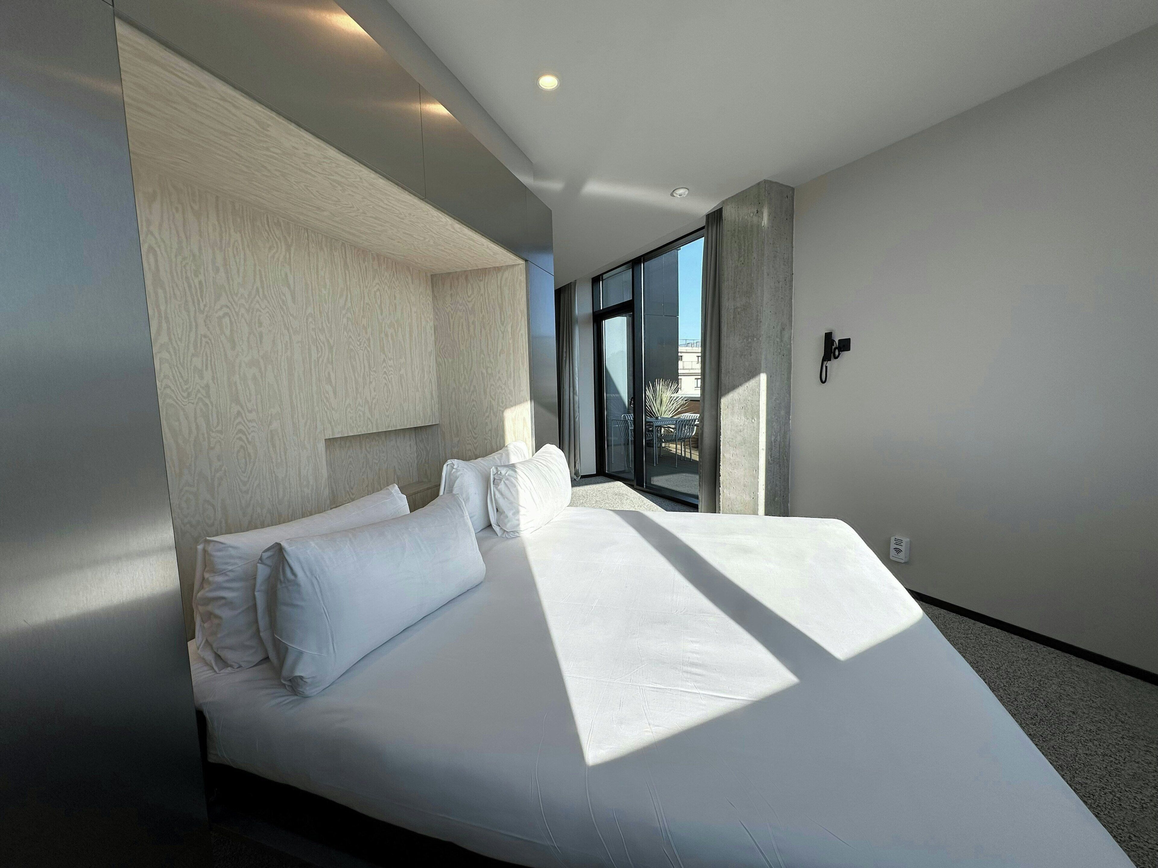 Una habitación de hotel moderna con una cama grande, vistas al exterior y un diseño minimalista.