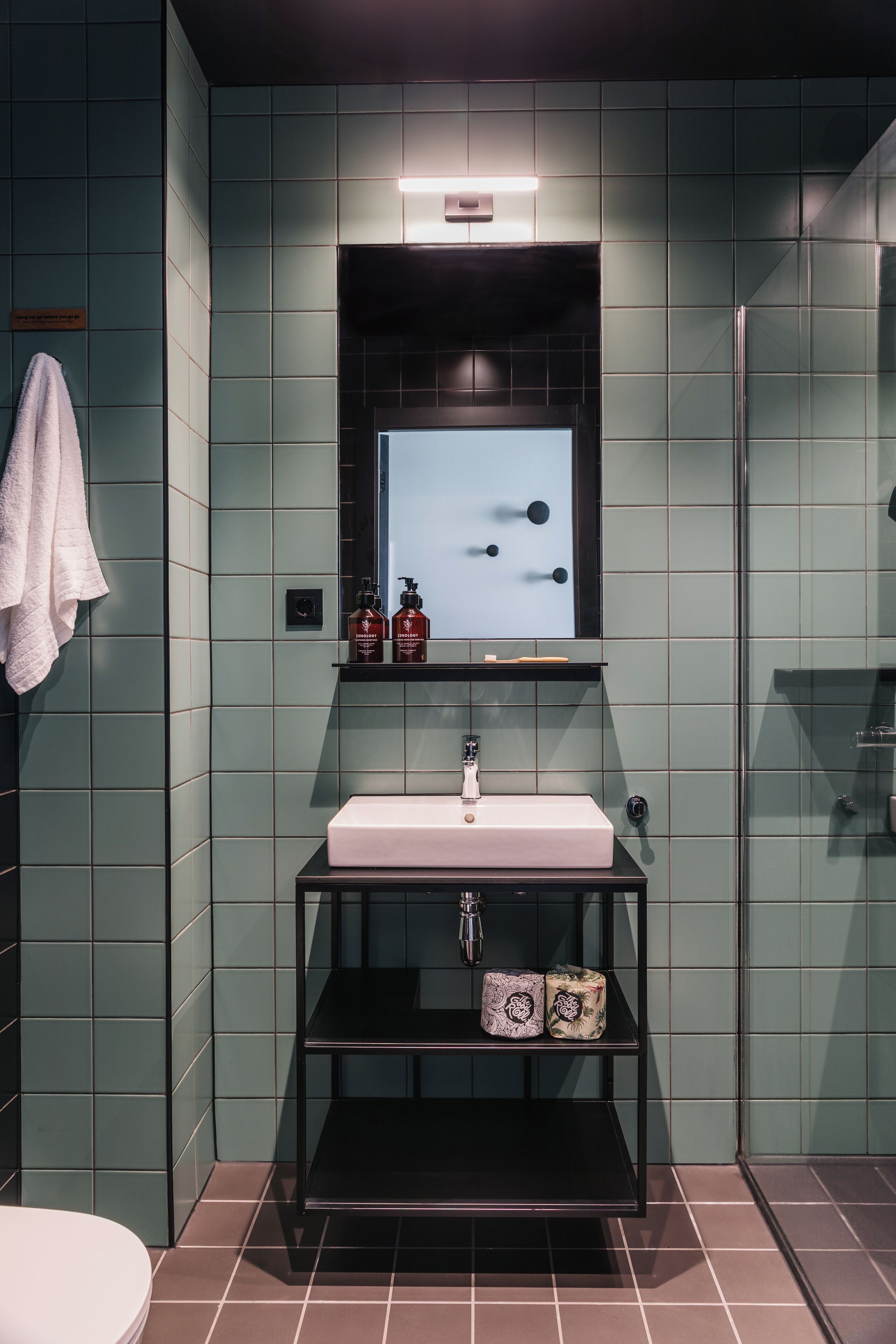Un baño moderno con un espejo rectangular, un lavabo blanco y una cabina de ducha de vidrio.
