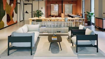Un espace de détente moderne avec des canapés, une table basse et un comptoir d’accueil.