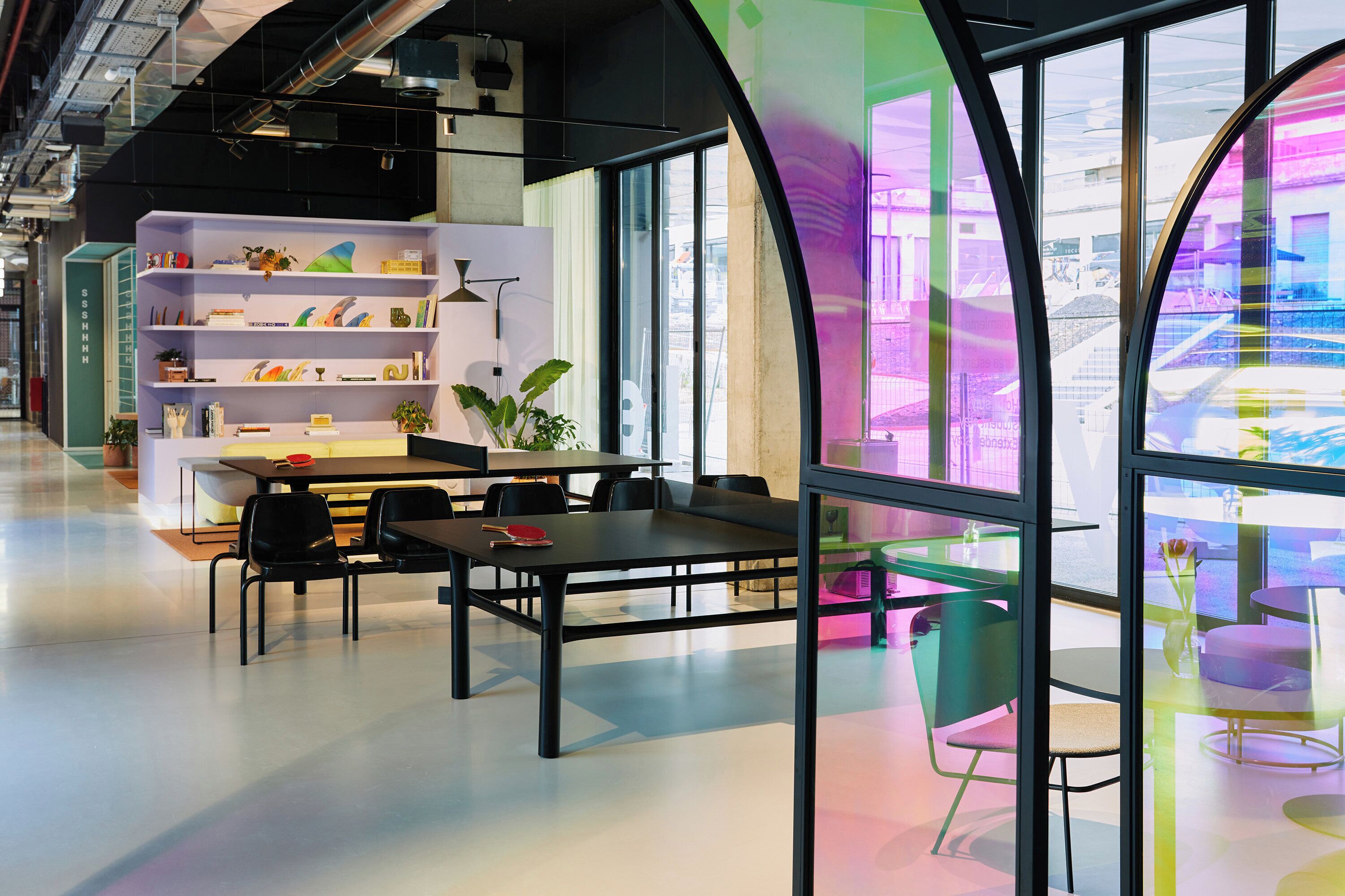 A modern interior with a dining area, bookshelves, and large windows.