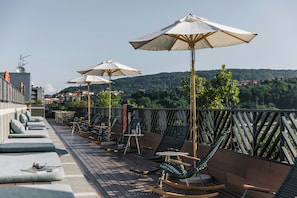 A rooftop terrace with outdoor seating, umbrellas, and a view of a hilly landscape. - The Social Hub San Sebastián (San Sebastián)