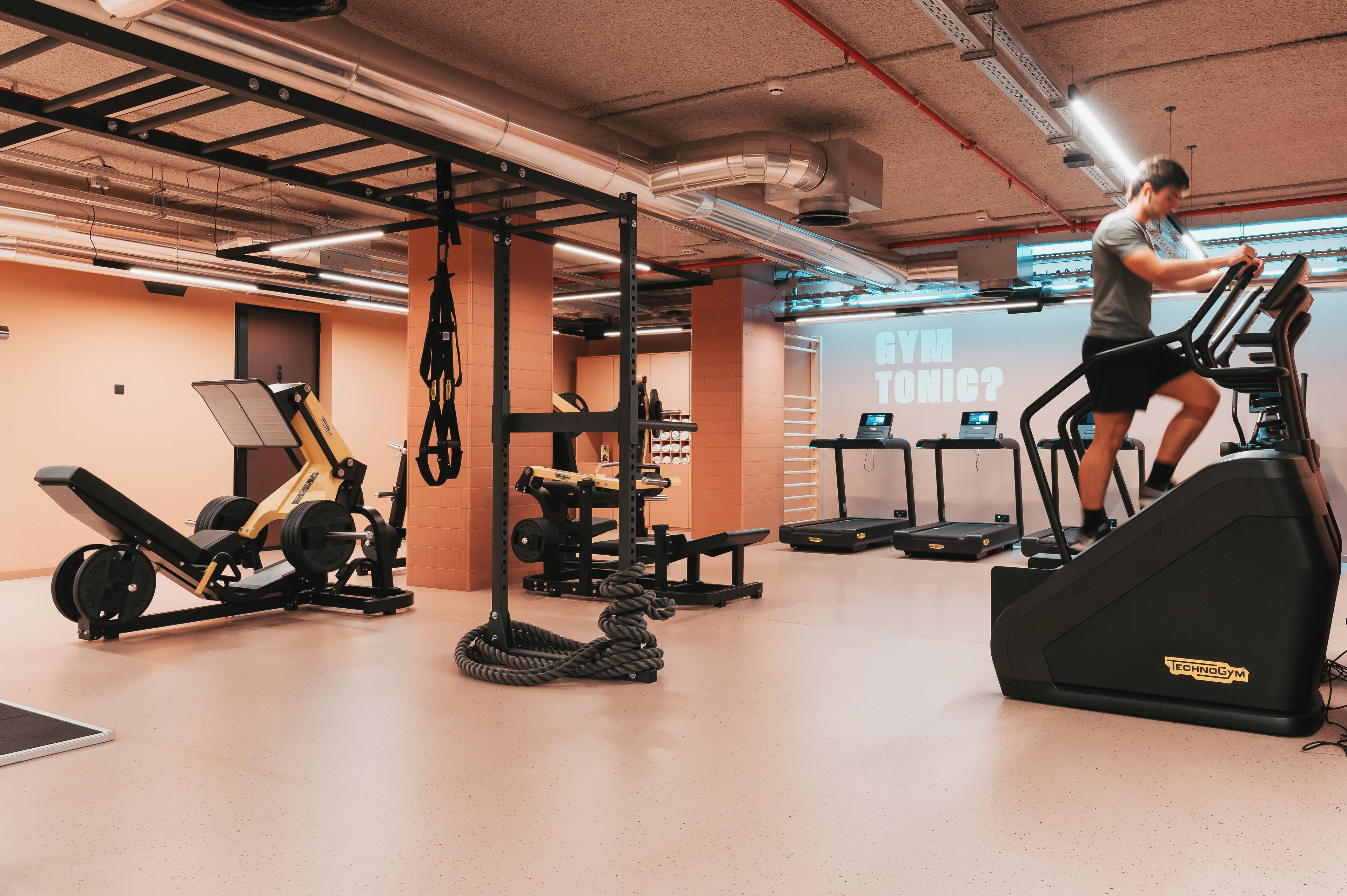 Une salle de sport équipée de tapis de course, d’appareils de musculation et d’une barre de traction.