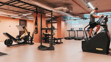 Un gimnasio con cintas de correr, máquinas de pesas y barra para dominadas.