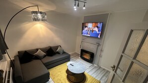 Ein modernes Wohnzimmer mit einer Couch, einem Kamin, einem Fernseher und einem Couchtisch.