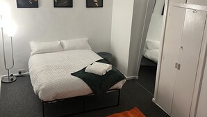 Ein Schlafzimmer mit einem Bett, einem Nachttisch, einem Spiegel und einem Kleiderschrank.