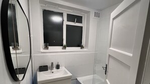Ein Badezimmer mit einem weißen Waschbecken, Spiegel und einer Badewanne.