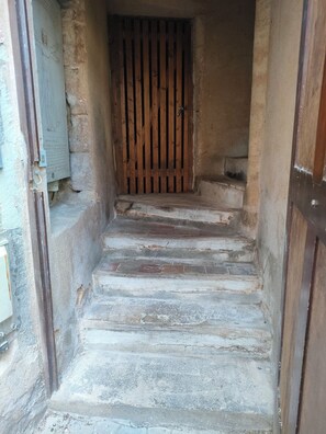 A narrow staircase with wooden steps leading to a door with vertical slats.