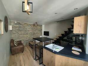 A modern kitchen with a black countertop, stainless steel sink, and a wooden cabinet.