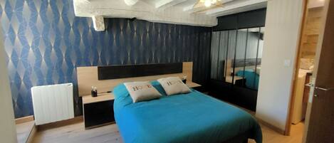 A bedroom with a bed, a nightstand, a mirror, and a radiator.