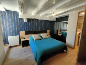 A bedroom with a bed, a nightstand, a mirror, and a radiator.