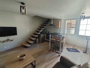 A compact living space with a kitchen, a dining area, and a staircase.