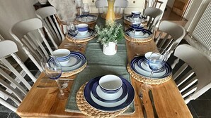 A dining table set with blue and white plates, a woven placemat, and a potted plant.