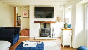 A living room with a fireplace, a television mounted on the wall, and a cozy seating area with a sofa and a chair.