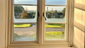 A window with a view of a rural landscape, including houses and greenery.
