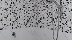 A shower with a handheld showerhead, a wall-mounted faucet, and a handheld showerhead with a control panel. - Beluga Sands Beach (Ambalangoda)