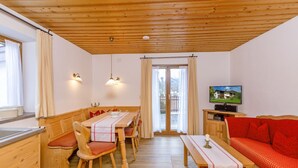 Una habitación acogedora con techo de madera, una mesa de comedor con sillas, un sofá y un televisor.