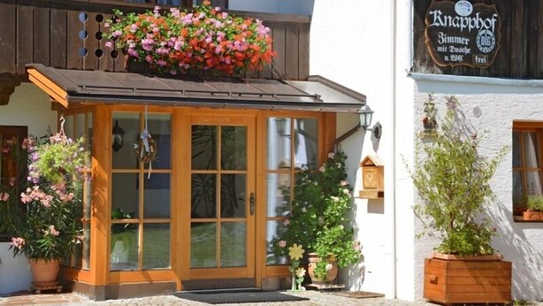 Il s’agit d’un bâtiment traditionnel, doté d’une porte d’entrée en bois, d’un panier de fleurs sur le toit et d’une enseigne indiquant qu’il s’agit d’un Knapphof.