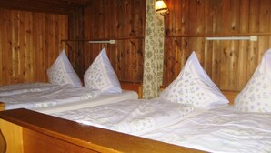 Une pièce en bois avec deux lits, chacun agrémenté de draps et d’oreillers à motifs floraux assortis.