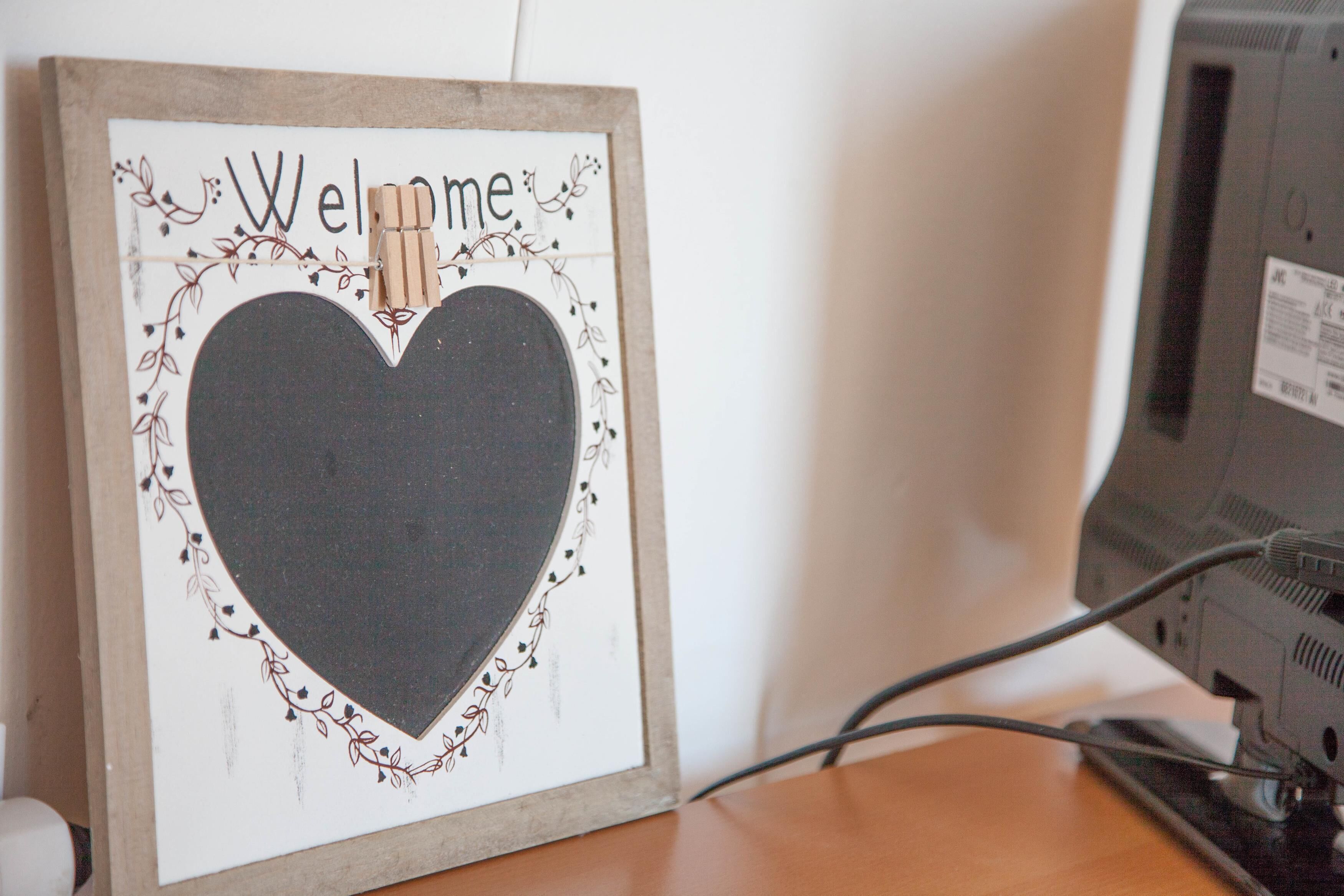 A framed welcome sign with a heart design and a clothespin.