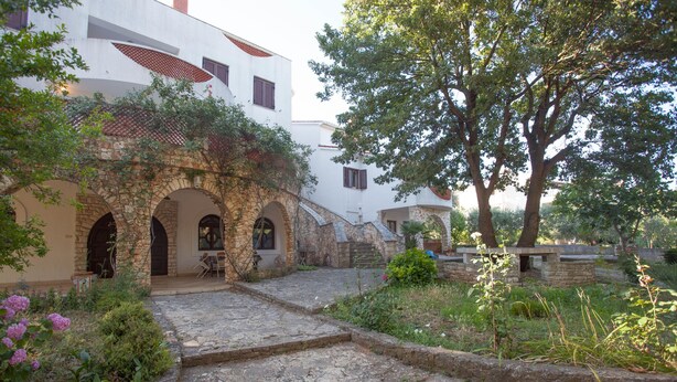 A courtyard with stone pathways, arches, and a tree. - Apartments and Room Agata (Medulin)