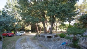 A paved pathway leading to a stone bench surrounded by trees. - Apartments and Room Agata (Medulin)