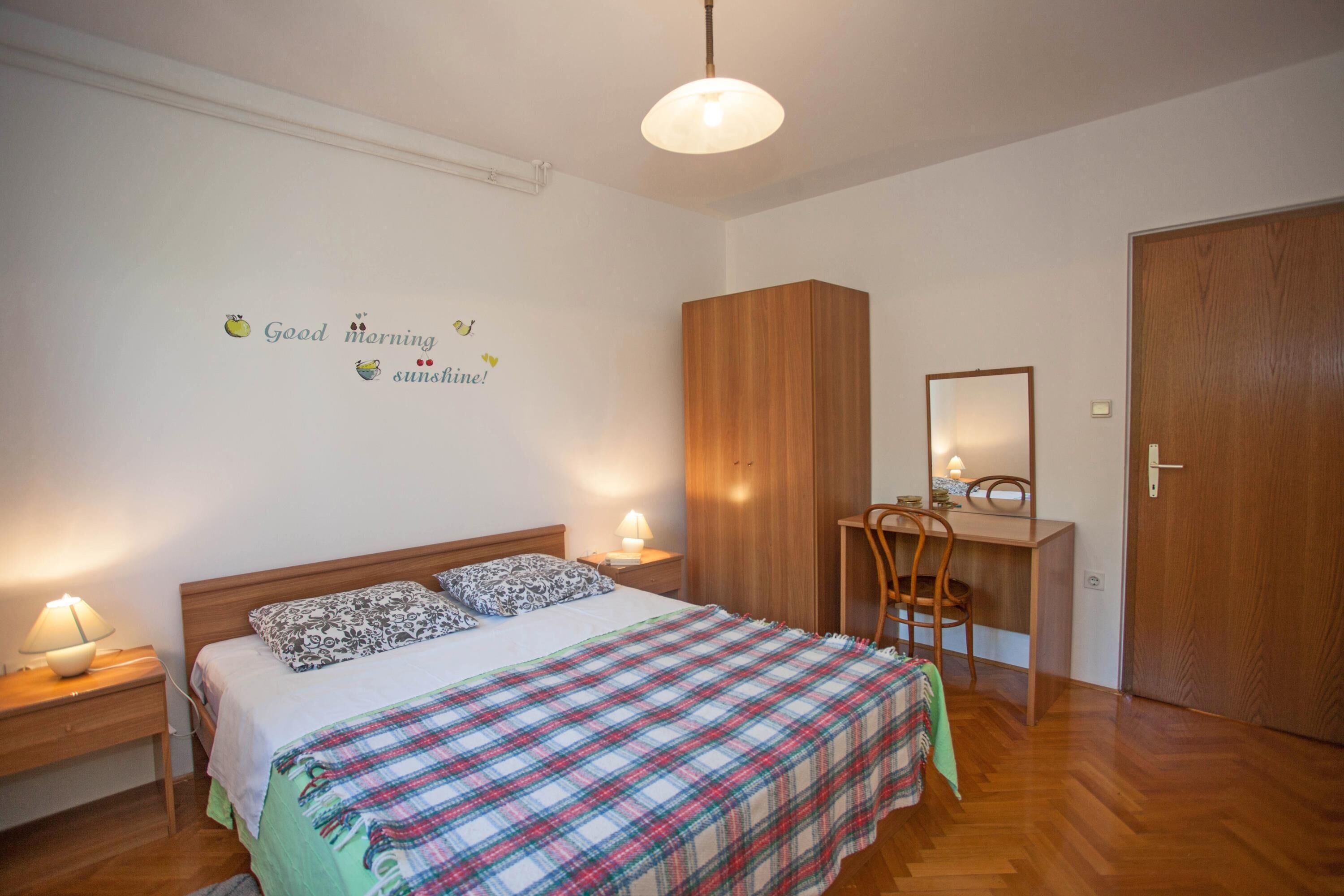 Un dormitorio con cama, lámparas de noche, escritorio y armario.