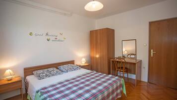Un dormitorio con cama, lámparas de noche, escritorio y armario.